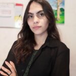 Mulher de casaco preto e cabelos longos pretos com as mãos cruzadas
