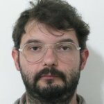 Homem de cabelos curtos, óculos e barba.