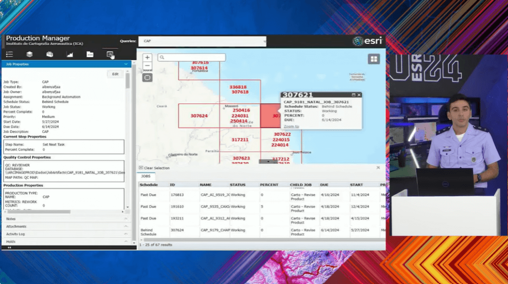 Oficial do Instituto de Cartografia Aeronáutica (ICA) apresenta painel do ArcGIS Production Manager. A tela mostra uma interface do software com um mapa do Nordeste do Brasil, destacando diversas áreas identificadas por códigos e status de produção, enquanto o oficial está ao lado, em uniforme, explicando o painel durante o evento Esri 2024.