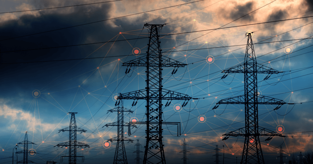 Torres de transmissão de energia elétrica ao entardecer, com nuvens carregadas ao fundo. Linhas conectadas a ícones de tecnologia e dados sugerem a integração de sistemas inteligentes e análises para o gerenciamento da rede elétrica.