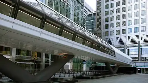 Passarela elevada de design moderno, em estrutura metálica e vidro, ligando edifícios corporativos em um ambiente urbano.