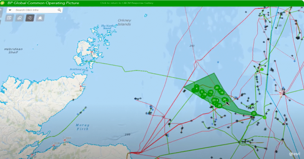 Imagem de uma interface de sistema GIS da BP (British Petroleum), intitulada "BP Global Common Operating Picture", exibindo uma visualização geoespacial da região marítima ao norte da Escócia, incluindo as Ilhas Órcades e o Estreito de Pentland. A tela apresenta camadas de informações como rotas de cabos ou oleodutos (linhas vermelhas e verdes), agrupamentos de plataformas marítimas (ícones de cruzes e círculos numerados), além de áreas destacadas em verde, representando zonas operacionais ou de monitoramento. Interface com logotipo da Esri visível no canto inferior direito.