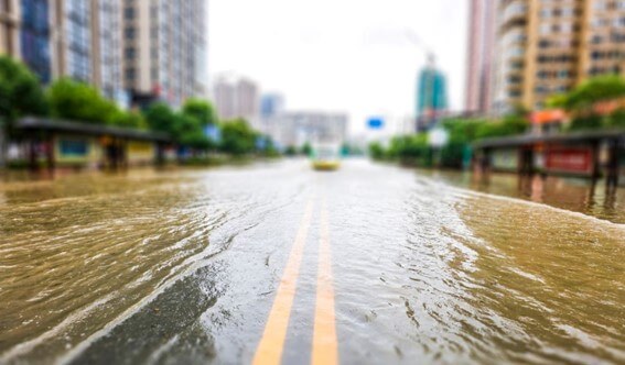 Rua alagada após forte chuva, ilustrando a necessidade de sistemas de drenagem eficientes para prevenir enchentes urbanas.