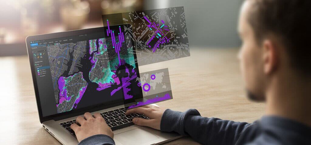 Profissional utilizando o ArcGIS no notebook para análise geoespacial, com mapas, gráficos e camadas de dados interativos em destaque.
