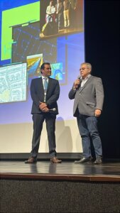 Guilherme Viana, executivo da Imagem, fala ao público com o banner do evento ao fundo