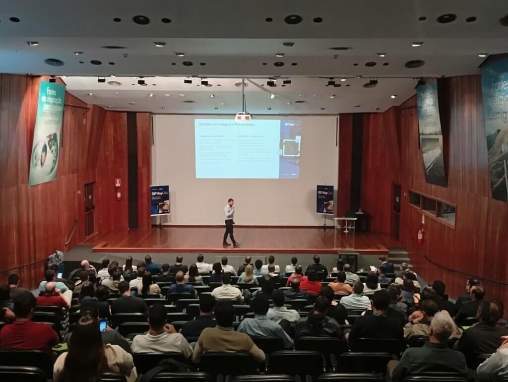 Auditório do 3º GIS Day Gás em Belo Horizonte durante apresentação técnica, com público assistindo palestra sobre gestão estratégica e governança no setor de gás natural.