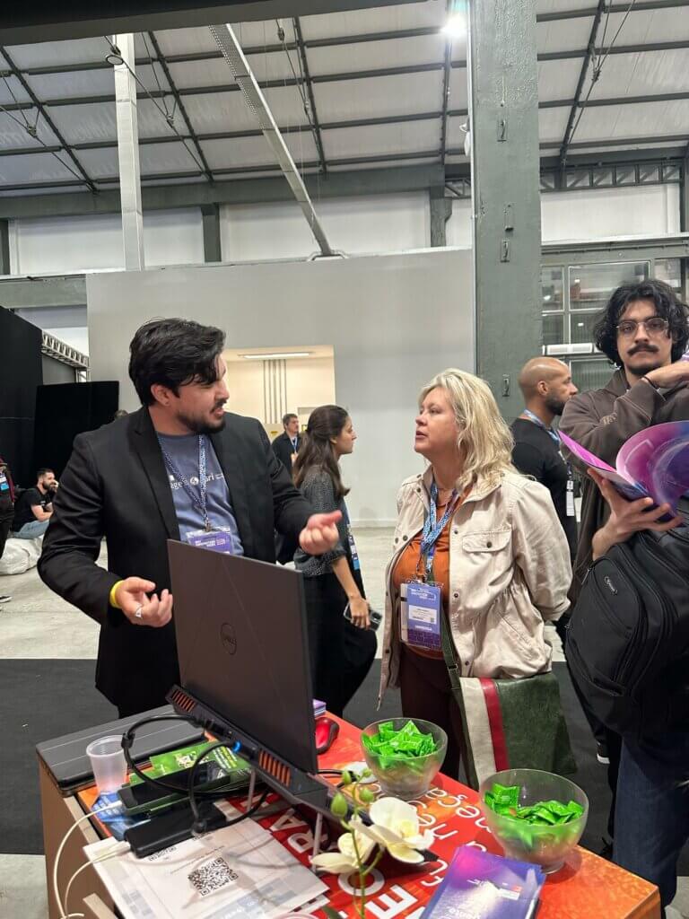 Especialista da Imagem Geosistemas conversa com participante no estande durante o Rio Innovation Week 2024.