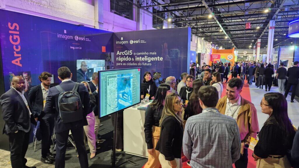 Estande da Imagem Geosistemas no Connected Smart Cities 2025, com visitantes explorando soluções ArcGIS em tela interativa e equipe recebendo o público para apresentar tecnologias de inteligência geográfica.